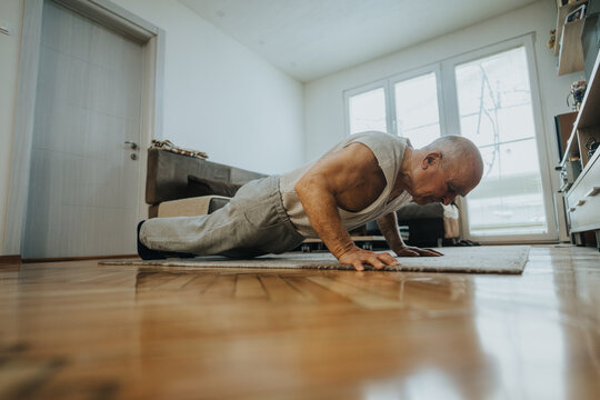 An older man demonstrating strength and fitness through push-ups on a rug in a well-lit and cozy living room, symbolizing health, vitality, and an active lifestyle.