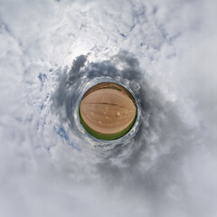 simple little tiny planet without buildings in blue sky with sun and beautiful clouds. Transformation of spherical panorama 360 degrees. Spherical abstract aerial view. Curvature of space.