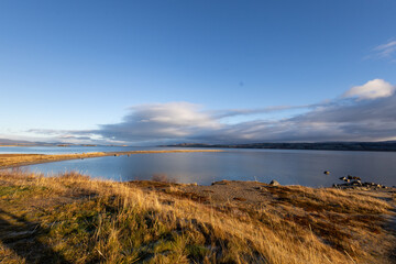 The Norwegian landscape unfolds in its full beauty, with towering mountains perfectly mirrored in the calm waters of a fjord. The natural mirror of the water captures every detail of the surroundings,