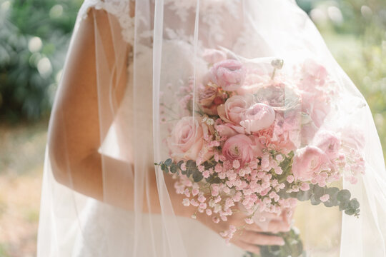 The bride with the pink bouquet wears a white dress with a white veil.