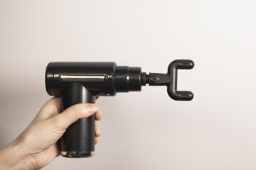Woman holding percussion massage gun with small U head nozzle for vertebrae. Physiotherapy, muscle recovery, self-massage tool. Healthcare. Close up.
