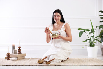 Woman with singing bowls on floor indoors. Space for text