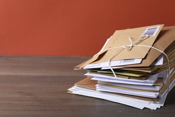 Post office. Stack of different paper envelopes on wooden table, closeup. Space for text