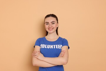 Portrait of smiling volunteer with crossed arms on beige background