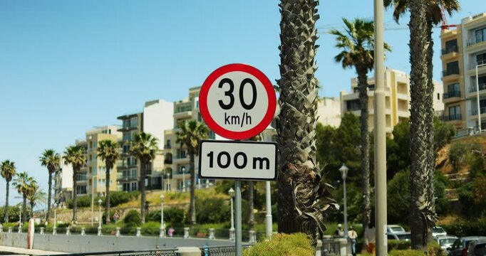 Traffic regulation board reducing speed for following part of route near bay. Road sign informing drivers about pace limits on concrete section of street