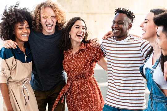Young group of people having fun together outdoor. Multiracial friends laughing while hugging each other outside. Youth community concept