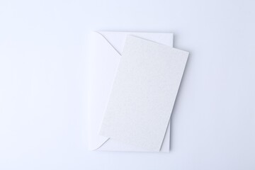 Blank greeting card and paper envelope on white background, top view