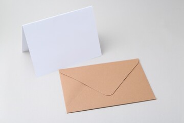 Blank greeting card and paper envelope on light background