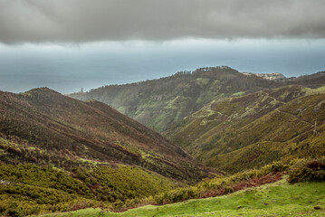 Obraz premium PR6, 25 Fontes hike, Levada do Risco, Arco da Calheta, Madeira Island, Portugal: Cloudy sky over green hills and ocean horizon