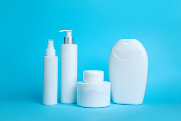 Collection of white cosmetic bottles with different shapes on a blue background. Ideal for beauty, skincare, and product packaging concepts. Minimalist design with clean, modern aesthetics.