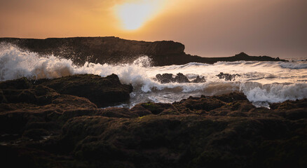 Dramatic waves crashing against rocky shore at sunset on north beach, Essaouira, Morocco