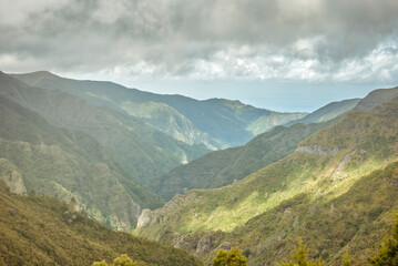 Fototapeta premium PR6, 25 Fontes hike, Levada do Risco, Arco da Calheta, Madeira Island, Portugal: Cloudy sky over green mountain range landscape
