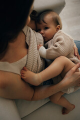 Young woman breastfeeding her baby at home
