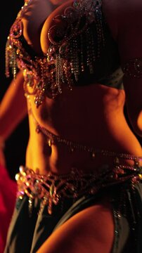 Dancer in red and blue oriental costumes dance belly dance on the black background