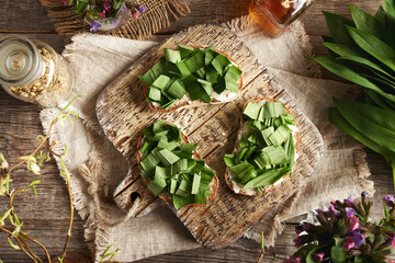 Chopped wild garlic leaves on slices of bread, top view