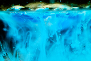 Blue ink bubbles floating in water with green highlights