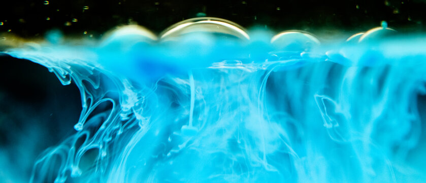 Turquoise and blue ink bubbles flowing in water