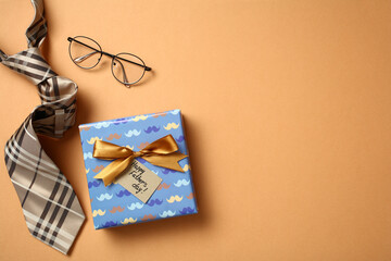Top view of a Father's Day gift with glasses and tie on orange background
