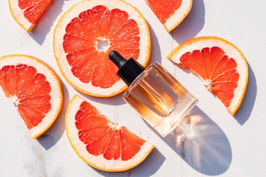 Essential oil bottle with fresh grapefruit slices in sunlight