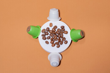 Biodegradable coffee capsules and beans on orange background, flat lay