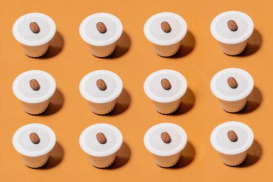 Biodegradable coffee pods with beans on orange background