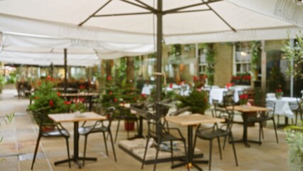 Blurred outdoor cafe in london with tables and chairs set under umbrellas in a bokeh-rich winter or autumn setting, evoking a festive, cozy atmosphere.