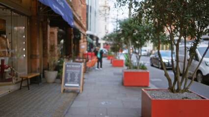 Street view in london during winter with defocused background highlighting urban life and blurred man walking along sidewalk with trees.