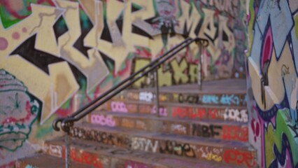 Blurred street scene with vibrant graffiti covering urban walls in an outdoor setting, emphasizing artistic and defocused elements with a gritty ghetto atmosphere.