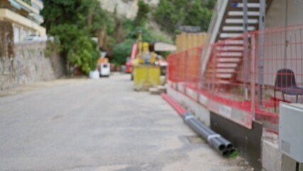 Blurred construction site with defocused bokeh background showing industrial materials and safety barriers during daylight in an urban working environment outdoors.