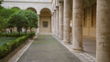 Blurred view of ancient university campus showing old stone columns and lush green garden creating a serene outdoor academic environment under an arched building facade.