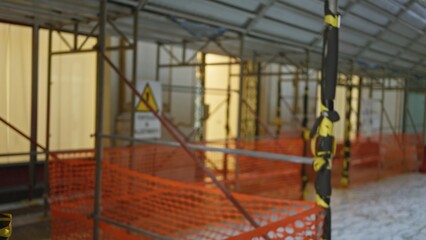 Naklejka premium Blurred image of construction site with scaffolding and safety barriers highlighted by bokeh lighting, creating a defocused urban working environment.