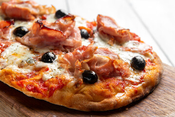 Pinsa romana con prosciutto, mozzarella, sugo e olive nere, cibo italiano 
