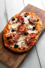 Pinsa romana con prosciutto, mozzarella, sugo e olive nere, cibo italiano 