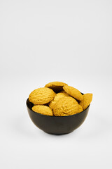 A plate of cookies sits on a white background. The cookies are small and round, and all the same color. The plate is black, and the cookies are arranged in a pyramid shape, one on top of the other.