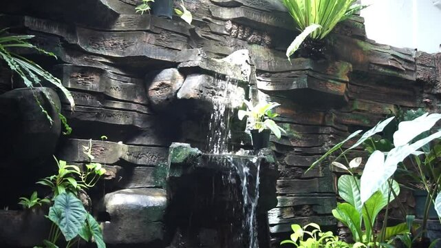 artificial mini waterfall and artificial rock wall and flowing water in artificial fish pond, and some beautiful ornamental plants