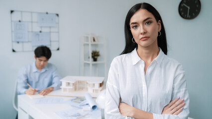 Obraz premium Closeup of female professional architect engineer cross arms with confident while skilled coworker focus on drawing blueprint at table with house model. Creative living and design concept. Immaculate.