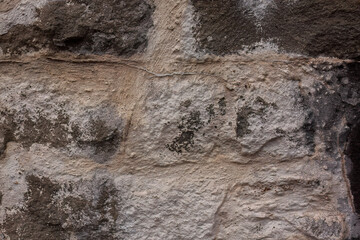 Weathered stone wall with moss and textured surface
