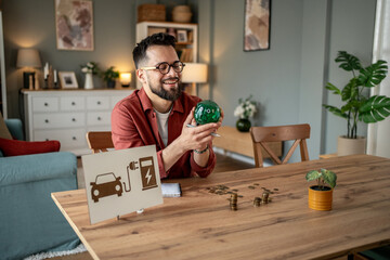 Man saving money for electric car using piggy bank at home