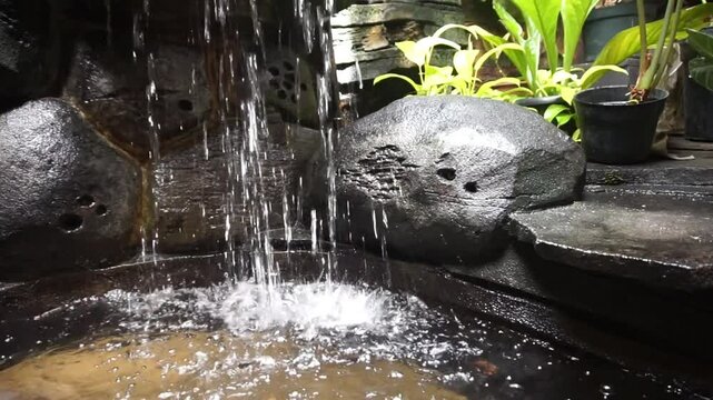 artificial mini waterfall and artificial rock wall and flowing water in artificial fish pond, and some beautiful ornamental plants