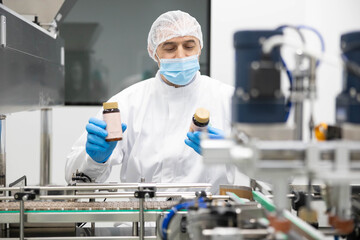 A worker in the production of supplements works at a machine that sorts and counts products....