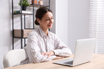 Smiling online speaker streaming webinar with laptop at table indoors