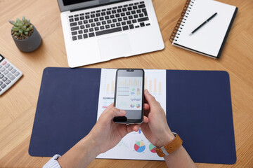 Man taking photo of document using scanning app on smartphone at desk in office, above view
