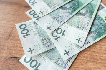 lot of polish banknotes of 100 PLN on wooden desk