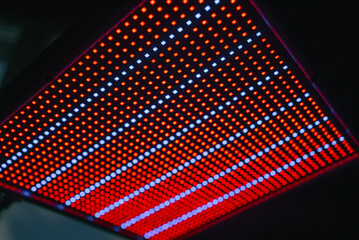 Red and blue light emitting diodes creating a captivating pattern on an led panel, filling the dark...
