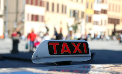 red writing TAXI on the automobile used for transporting paying people through the city streets