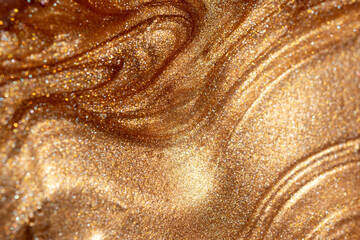 Texture background with golden shimmering cosmetic body spray or gel. Glowing backdrop.