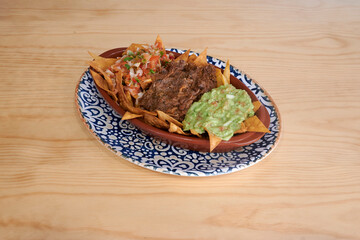 A plate of food with meat, beans, and tortilla chips. The beans are green and the meat is brown
