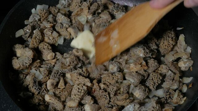 The cook fries morel mushrooms in a frying pan. Close-up. 