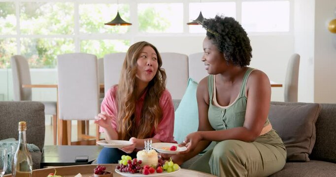 African American and Asian friends celebrating 30th birthday in dining room with cake and fruits