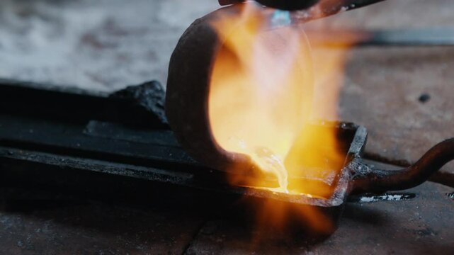 Jeweler pouring molten gold into ingot mold and heating it